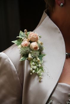 a close up of a person wearing a suit and tie with flowers on the lapel