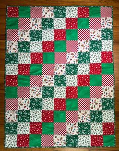 a green and red patchwork quilt sitting on top of a wooden floor