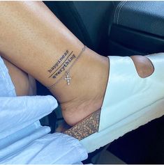 a woman's foot with a cross tattoo on her left ankle, sitting in a car