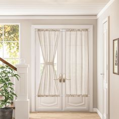 a white door with curtains and potted plant on the floor in front of it