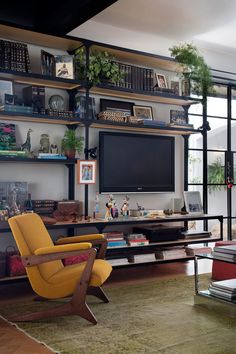 a living room filled with furniture and a flat screen tv on top of a wooden shelf