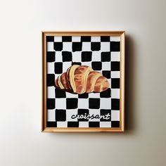 a framed painting of croissants on a black and white checkered background