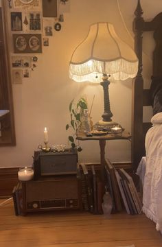 a bedroom with a bed, table lamp and books on the floor in front of it