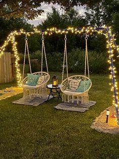 two chairs and a table are set up in the yard with lights strung across them