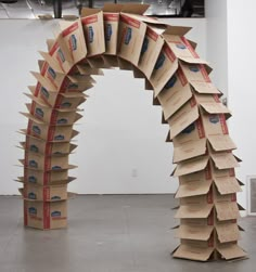 an arch made out of cardboard boxes in the middle of a room with white walls