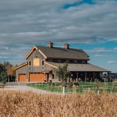 a large barn sits in the middle of an open field, surrounded by tall grass