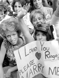 many people are holding up signs in the crowd