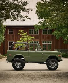 a green truck parked in front of a barn