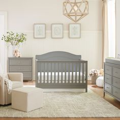 a baby's room with gray furniture and pictures on the wall, including a crib