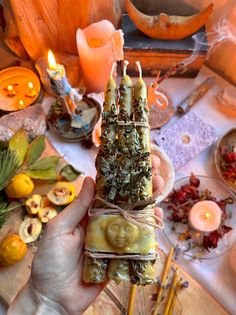 a person holding some kind of food on a table with candles and pumpkins in the background