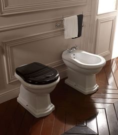 two white toilets sitting next to each other on top of a hard wood floored bathroom