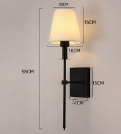 a wall light with a white shade on it and measurements for the lamp in front