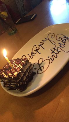 a piece of cake with candles on it sitting on a plate that says happy birthday