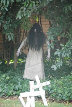 an instagramted photo of a creepy woman standing in front of a fence with trees and bushes behind her