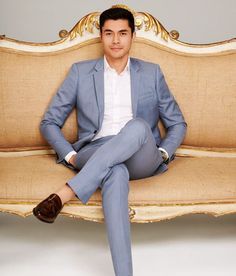 a man sitting on top of a couch wearing a blue suit and brown loafers