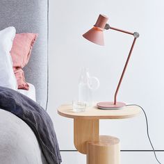 a bedroom with a bed, nightstand and lamp on the side table next to it