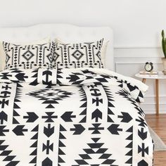 black and white bedding with an arrow pattern on the comforter, along with two night stands