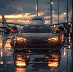 an audi car is parked on the tarmac at dusk with airplanes in the background