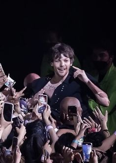 the man is surrounded by his fans and taking pictures with his cell phones in front of him