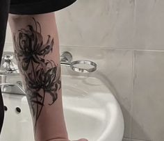 a woman's legs with black flowers on them in front of a bathroom sink