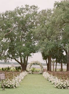 an outdoor ceremony setup with white flowers and greenery on the grass, surrounded by trees