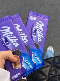 someone is holding three bars of oreo cookies in front of their feet and the bag