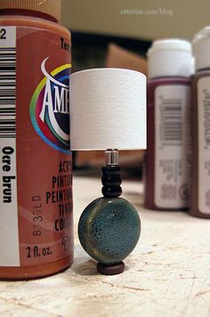 a lamp sitting on top of a wooden table next to bottles of glue and paint