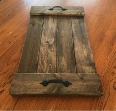 a wooden tray with handles sitting on top of a wood floor next to a window