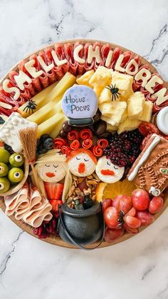 a platter filled with lots of different types of cheeses and fruit on top of a marble table