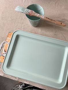 a blue tray sitting on top of a table next to a cup and wooden utensils