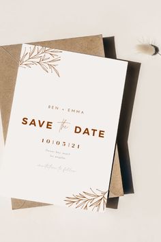 the save the date card is on top of some brown and white cards with gold foil