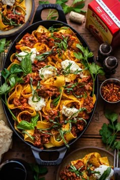 a large pot filled with pasta, meat and cheese on top of a wooden table