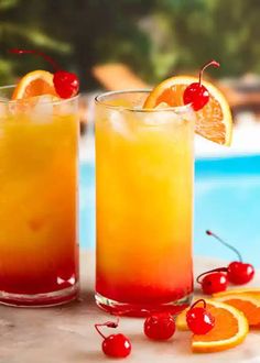 two glasses filled with drinks next to an orange slice and cherries on the rim