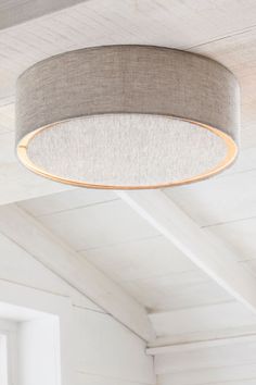 a round light fixture hanging from the ceiling in a room with white walls and wood flooring