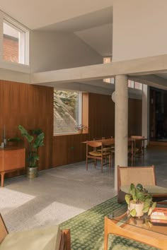 a living room filled with lots of furniture and wooden paneled walls next to a window