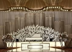 an elaborately decorated stage in the middle of a room with white furniture and chandelier