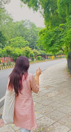 a woman is walking down the street with her hand up to something in the air