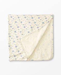 a blanket with blue and white flowers is folded on top of a white tablecloth