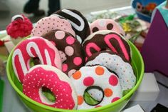 a green bowl filled with donuts covered in polka dot and pink frosting on top of a table