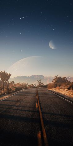 an empty road with no cars on it and the moon in the sky above them