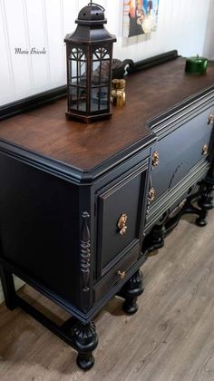 an old dresser is painted black and has a lantern on top