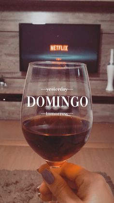 someone holding up a wine glass with the words domingo on it