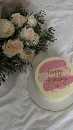 a birthday cake sitting on top of a table next to some flowers and a bouquet