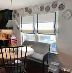 a kitchen table and chairs with plates on the wall above them in front of a window