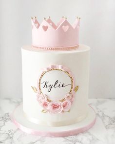 a white cake with pink flowers and a crown on top that says klylie