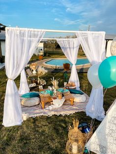 an outdoor party setup with balloons, cake and desserts on the grass near a swimming pool