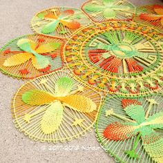 several circular doilys are on the floor in different colors and sizes, including green, yellow, red, orange