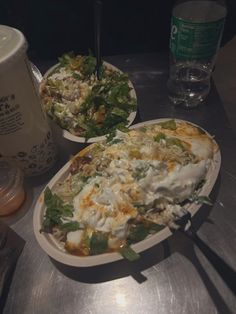 two plates filled with food sitting on top of a table next to cups and drinks