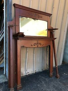 an old wooden mirror sitting on top of a table next to a metal wall mounted shelf