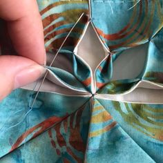 someone is stitching together some fabric to make an origami flower decoration with scissors